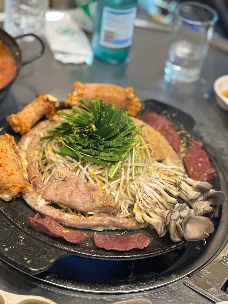 Beef gopchang grilling on a table griddle with vegetables