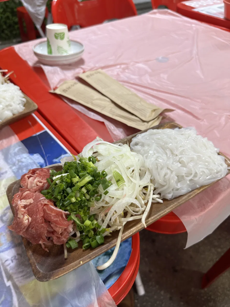 Pho ingredients arranged around a hot stone bowl at Bun Cha Kim