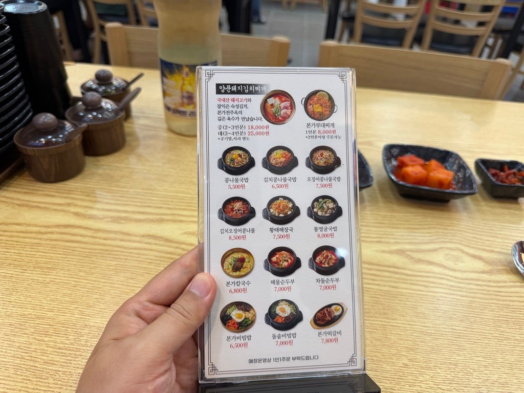 Menu board at Bonga Jeonjuok listing prices for various Korean dishes