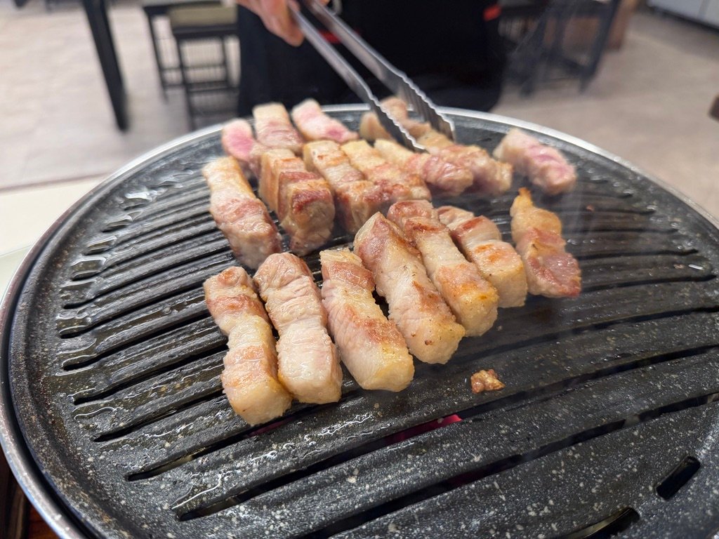 Cutting grilled samgyeopsal with scissors at the table