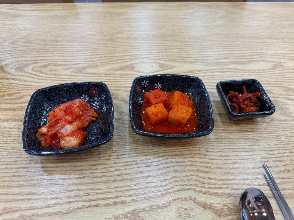 Three basic side dishes including kimchi and kkakdugi on a Korean table