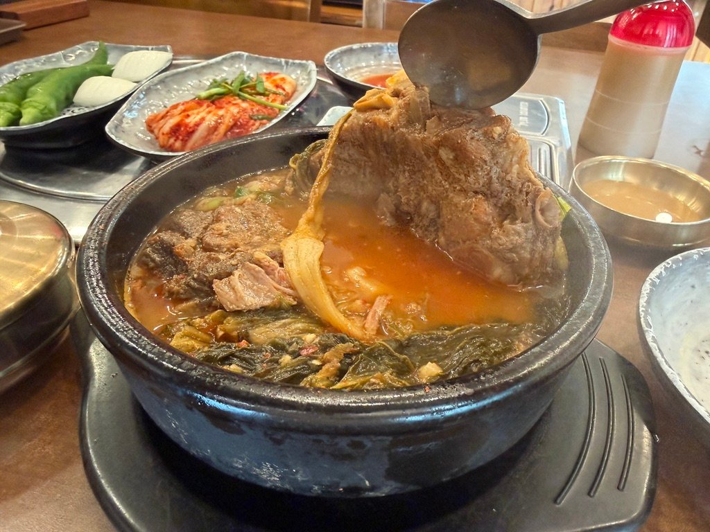 Close-up of a large pork spine bone lifted with chopsticks