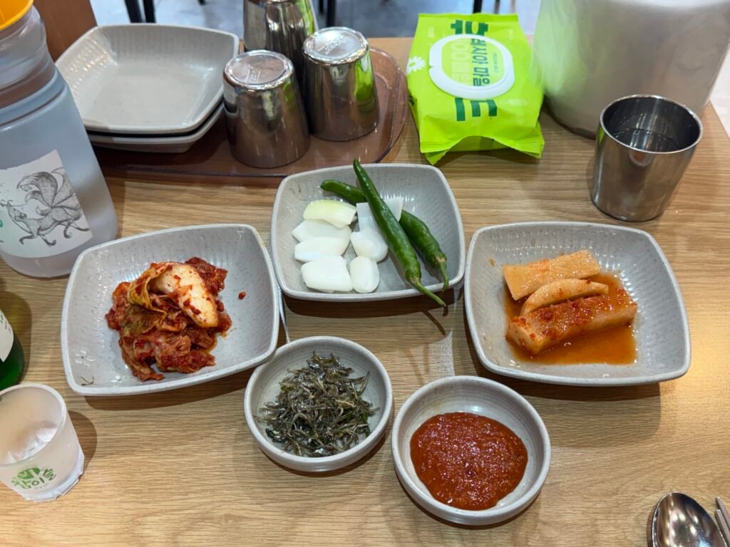 Assorted side dishes including kimchi, pickled radish, and dipping sauces
