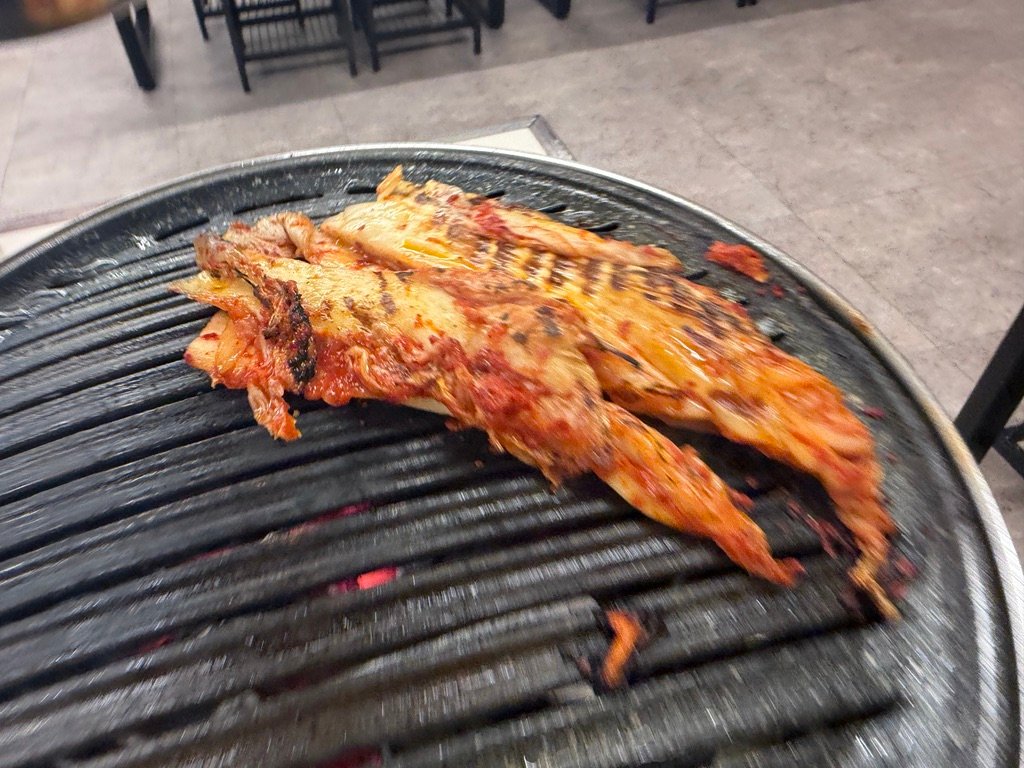 Kimchi grilling on a small charcoal brazier at a Korean BBQ table