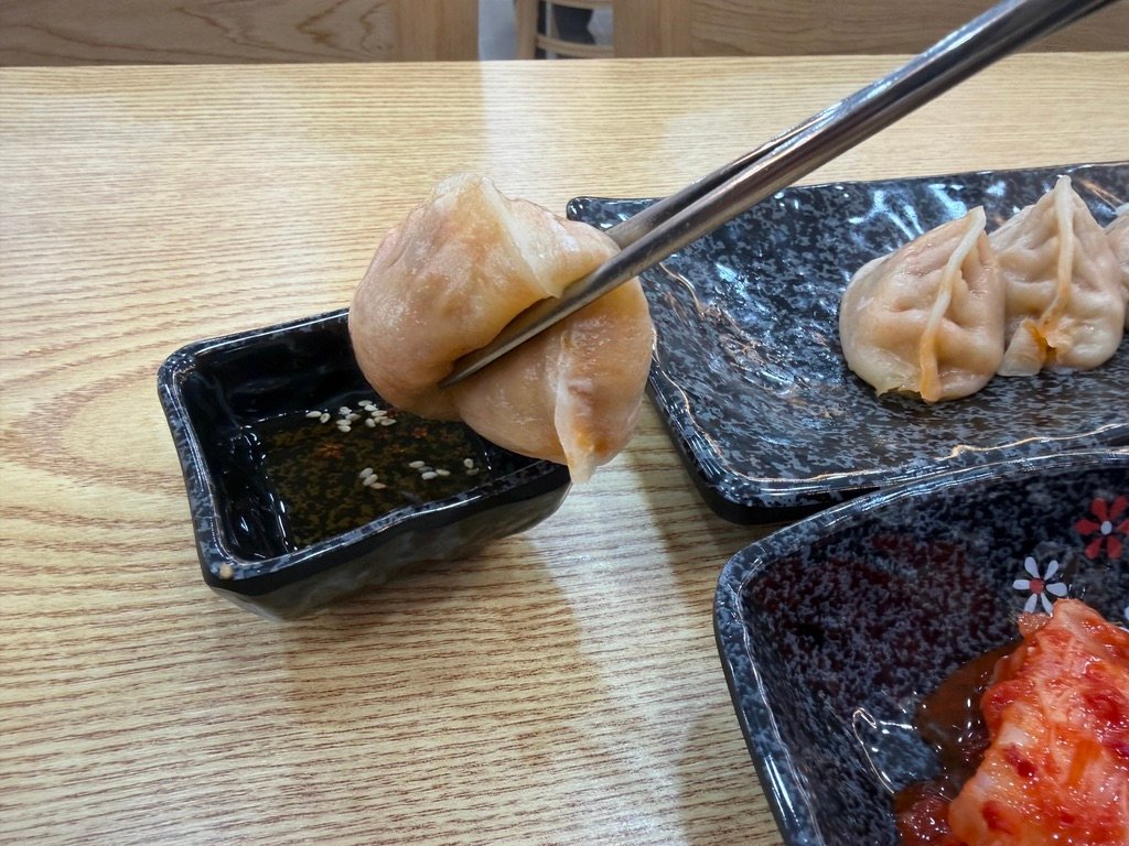 Close-up of chopsticks dipping kimchi mandu into sauce