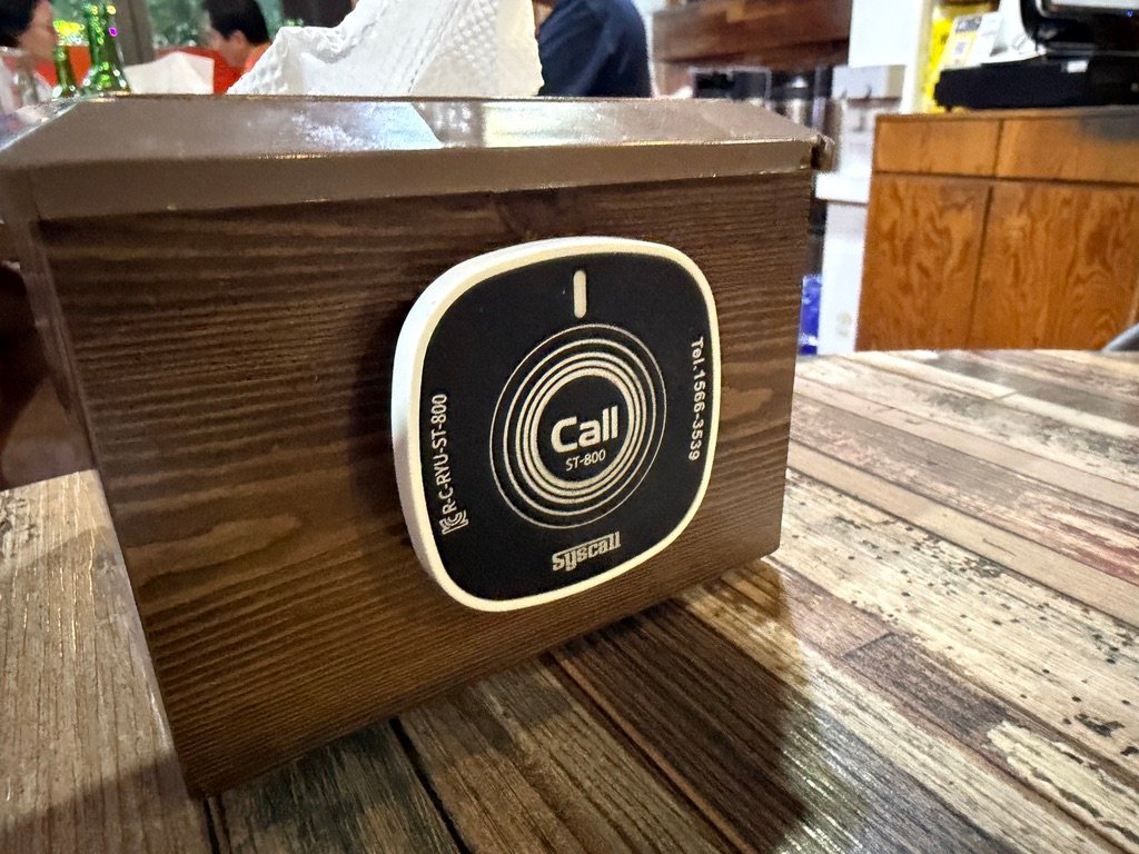 Round call bell on a table used to summon staff at Hook Chicken