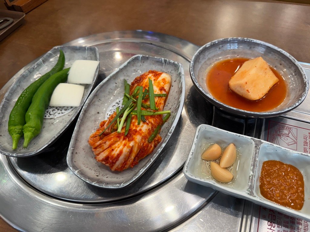 Korean banchan side dishes including green chili, cheese, and kimchi
