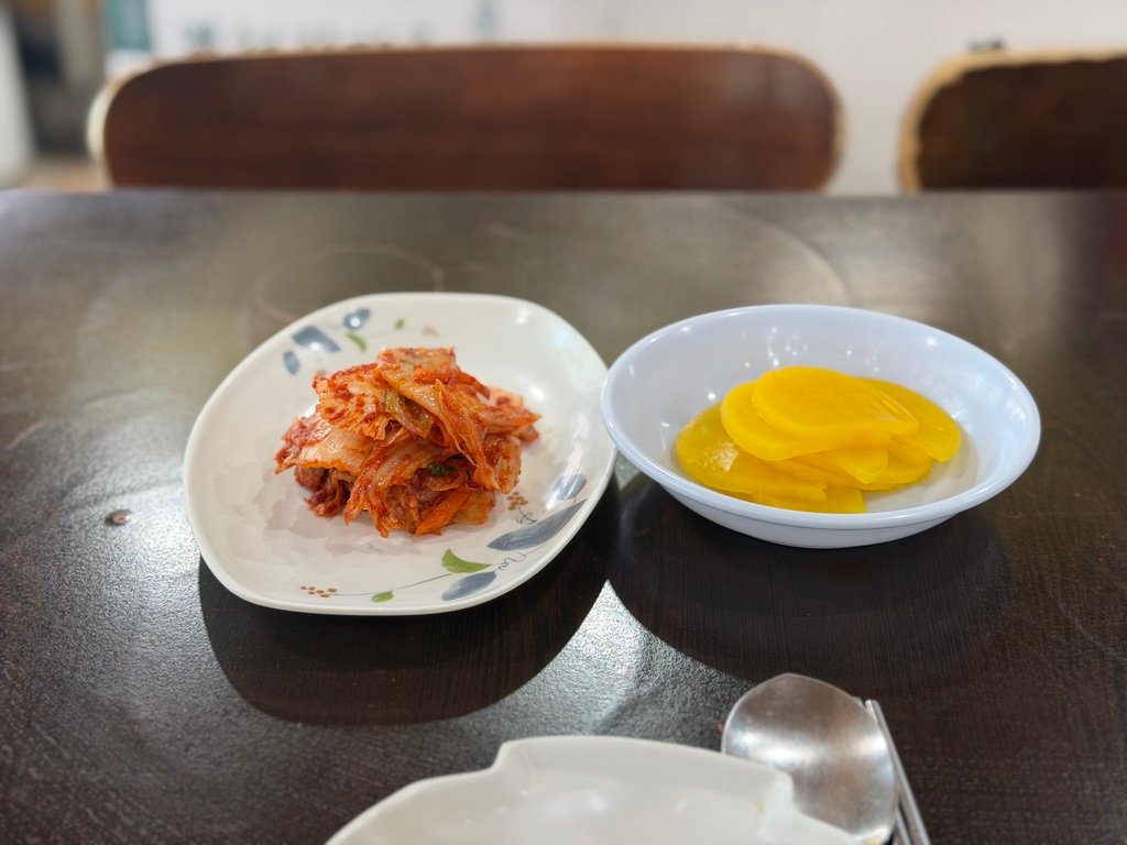 Side dishes of kimchi and pickled radish at a Korean kalguksu restaurant