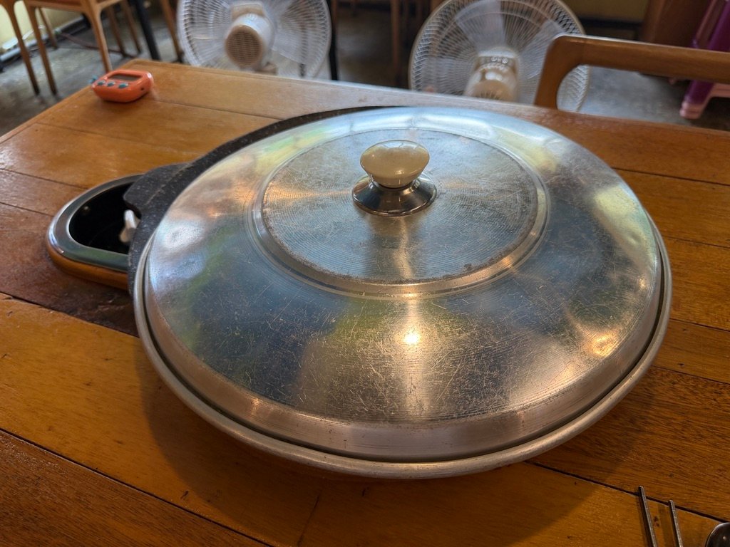 Pot of budae-jjigae bubbling while cooking at the table