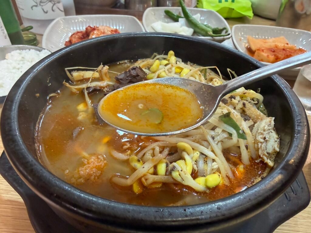 Spoon scooping haejangguk broth with beef tripe and bean sprouts