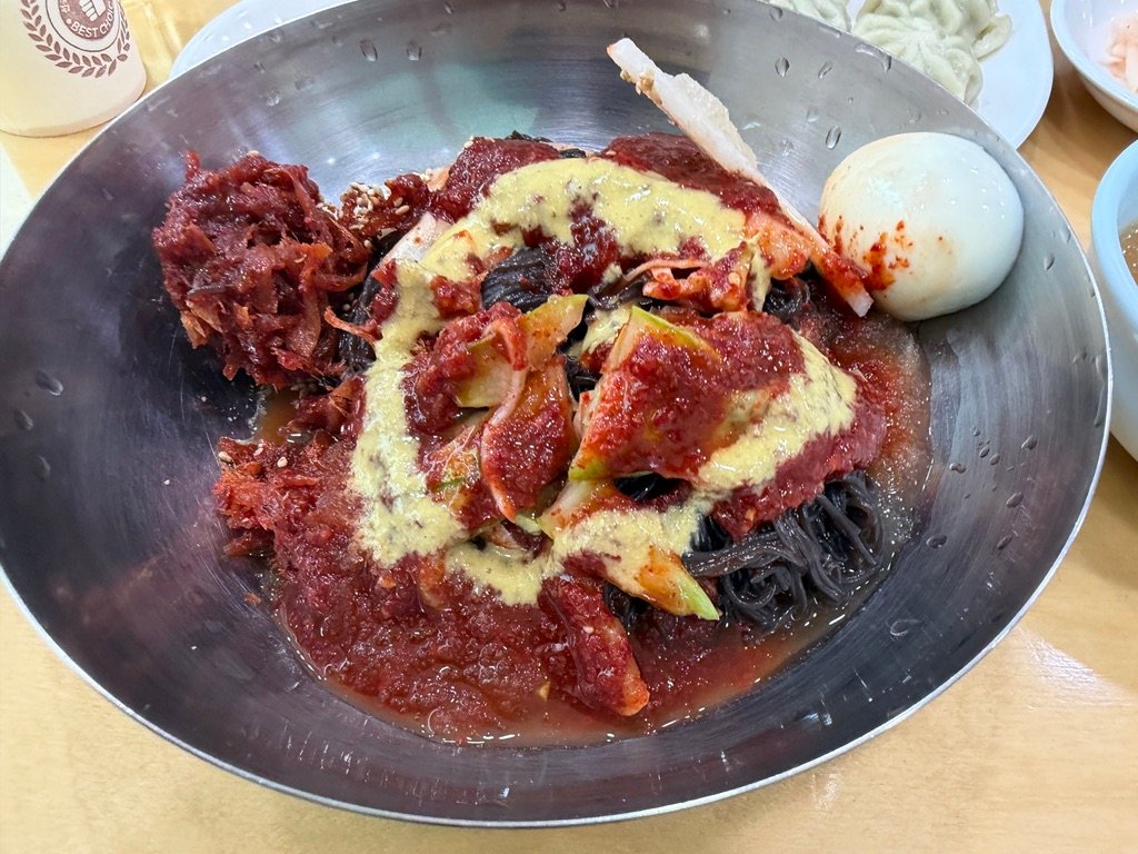 Finished bowl of naengmyeon after mixing in broth and sauce