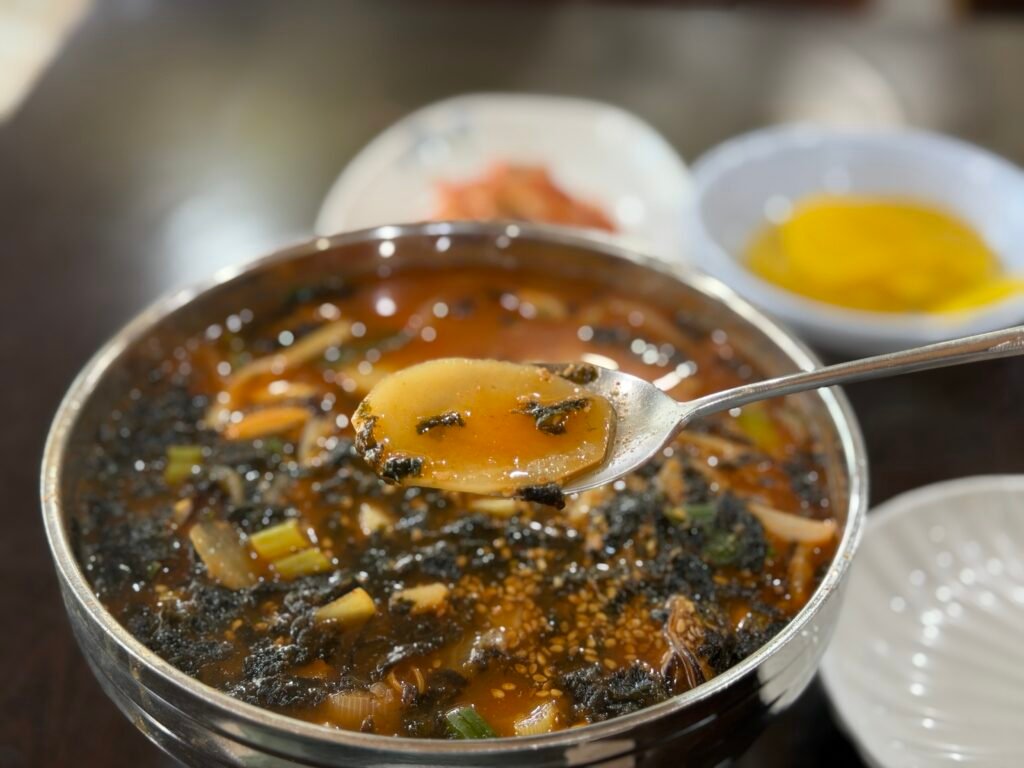 Spoon scooping up jang-kalguksu broth