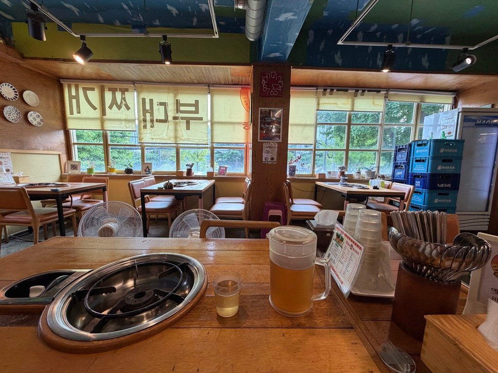 Interior seating at Boklaene Budae-jjigae with wood-toned tables