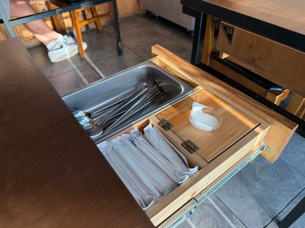 Table drawer holding spoons, chopsticks, and napkins