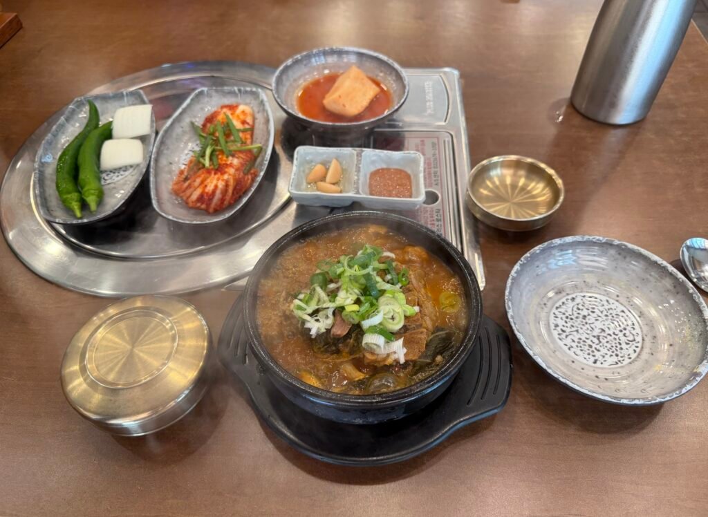 Bubbling pot of gamjatang with pork bones and side dishes at a Korean table