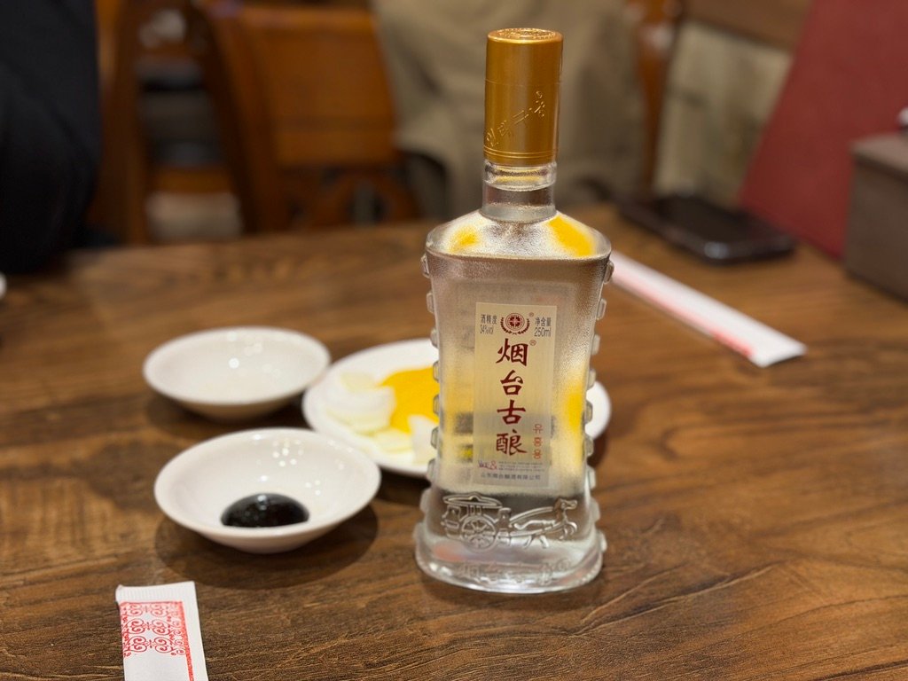 Tsingtao beer and Yantai Guniang Chinese baijiu liquor bottles on restaurant table