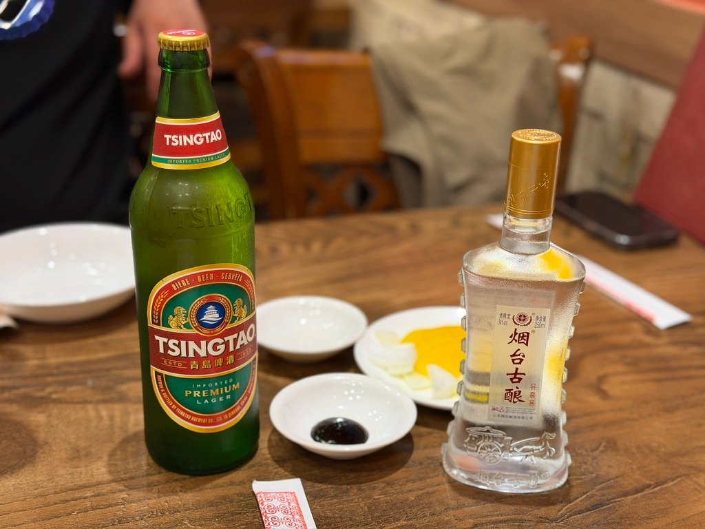 Tsingtao beer and Yantai Guniang Chinese baijiu liquor bottles on restaurant table
